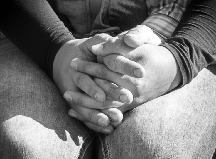 Black and white close up of a girlfriend holding her boyfriend's hand in her lap.