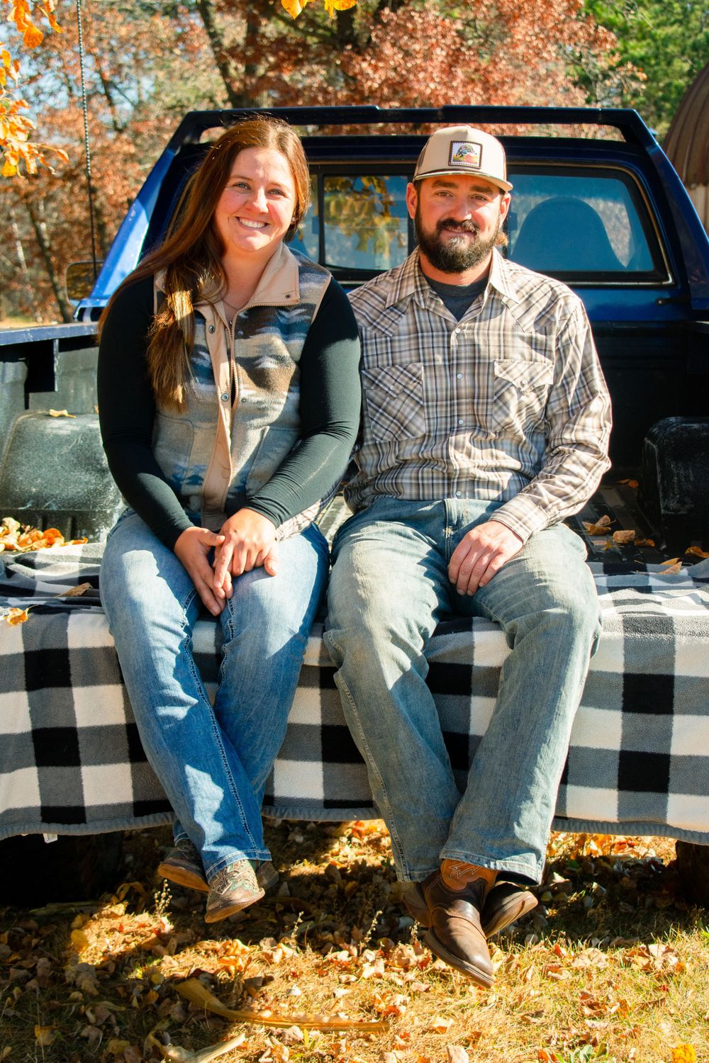 Girlfriend and boyfriend sitting on the tailgate of a 1984 Square body chevy. Girlfriend is holding boyfriend's hand.