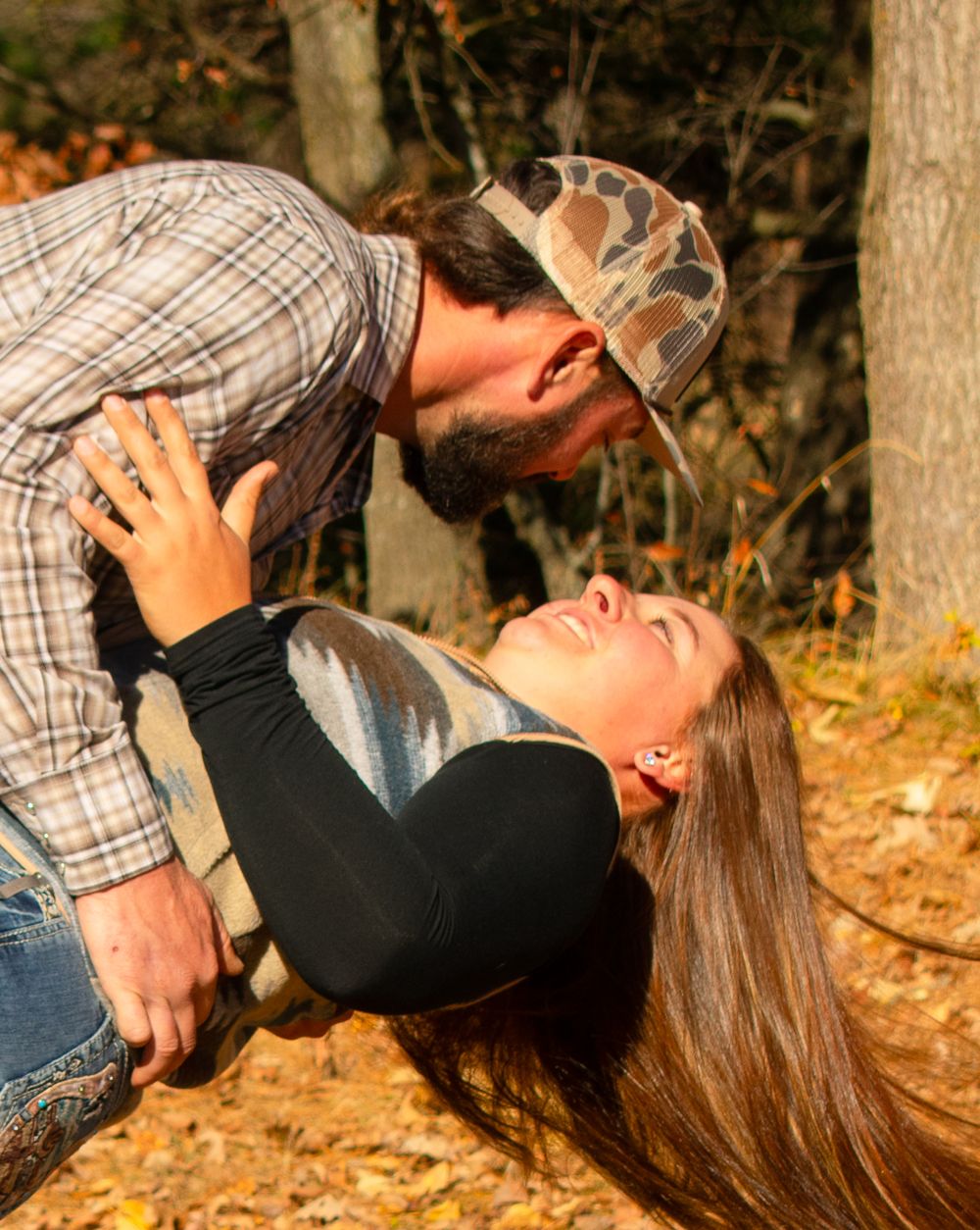 Boyfriend dipping girlfriend and both are smiling at each other.