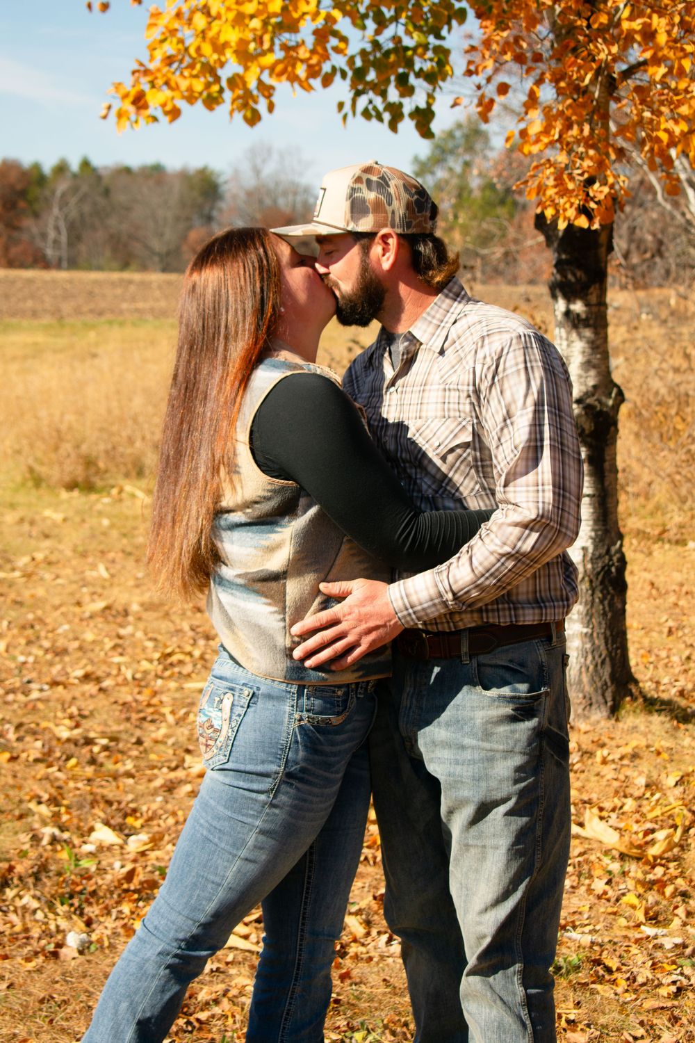 Boyfriend and girlfriend kissing in front of the Wisconsin fall colors.