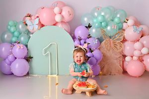 Pastel balloon arch decorations in pink, mint green, and purple colors arranged for a first birthday celebration party setup.