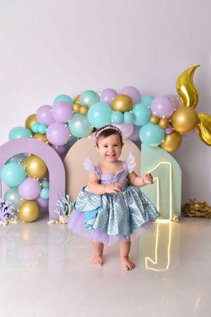 Pastel and gold balloon arch with neon number one sign creates magical first birthday party backdrop.