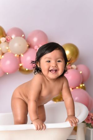 Baby bath photography with pink and gold balloon arch backdrop.