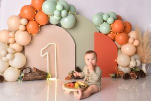 Fall-themed first birthday setup with pastel balloon arch and pumpkin decorations.