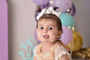 Purple themed cake smash photo session with twinkle lights and balloon decorations.