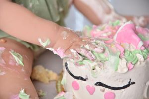 Close-up of decorating a unicorn-themed cake with pink and green frosting.