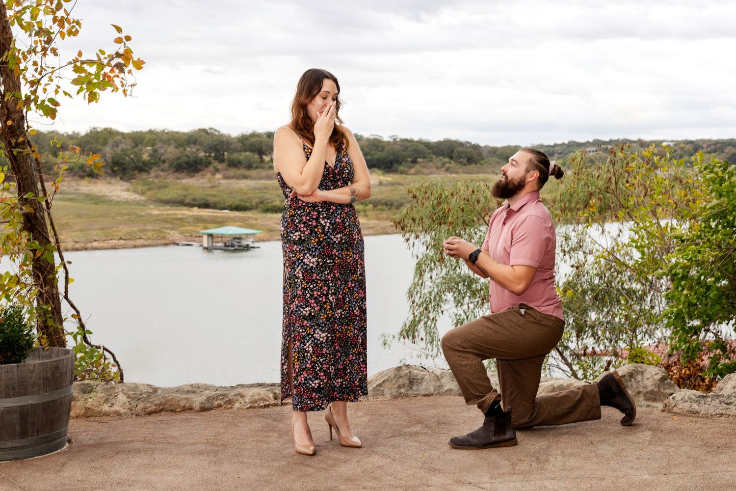 A scenic proposal moment unfolds on a lakeside overlook with autumn foliage framing the romantic scene.