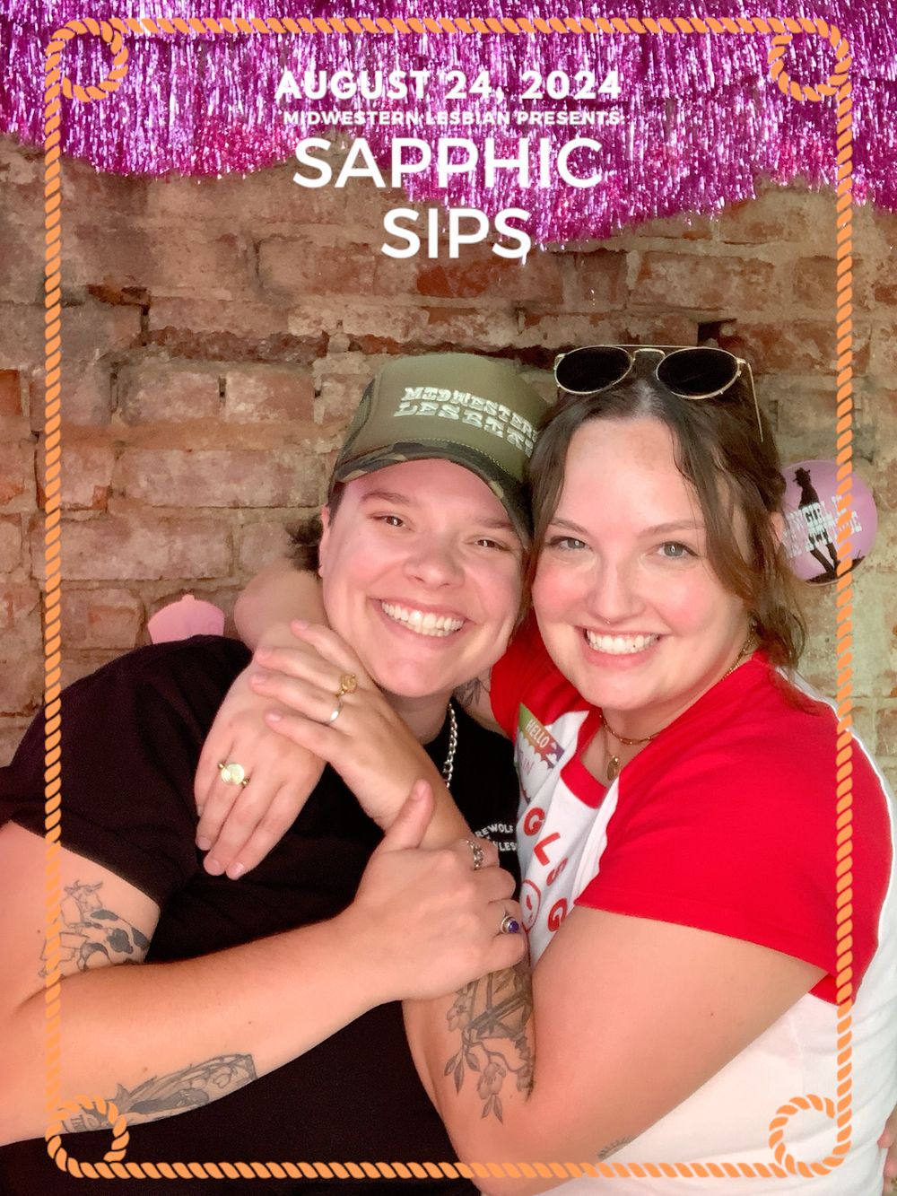 Event photo with pink tinsel backdrop showcasing fun celebratory moment at Sapphic Sips gathering.