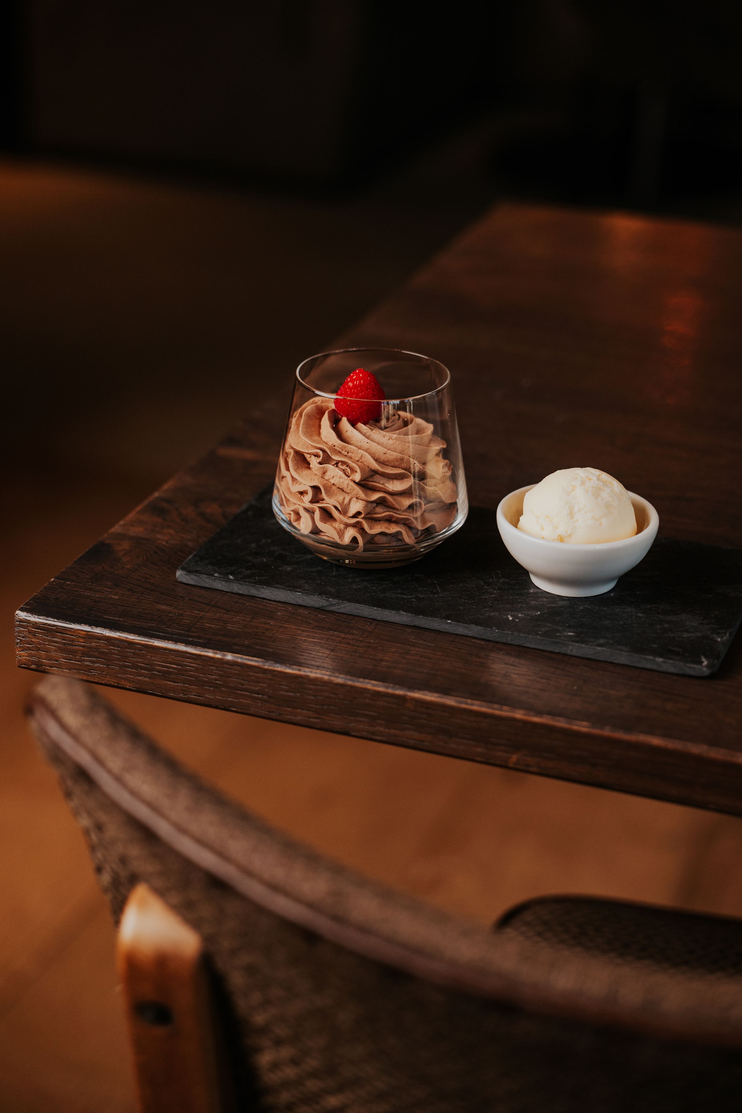 Elegant dessert presentation on dark wooden serving board with cream and berry garnish.