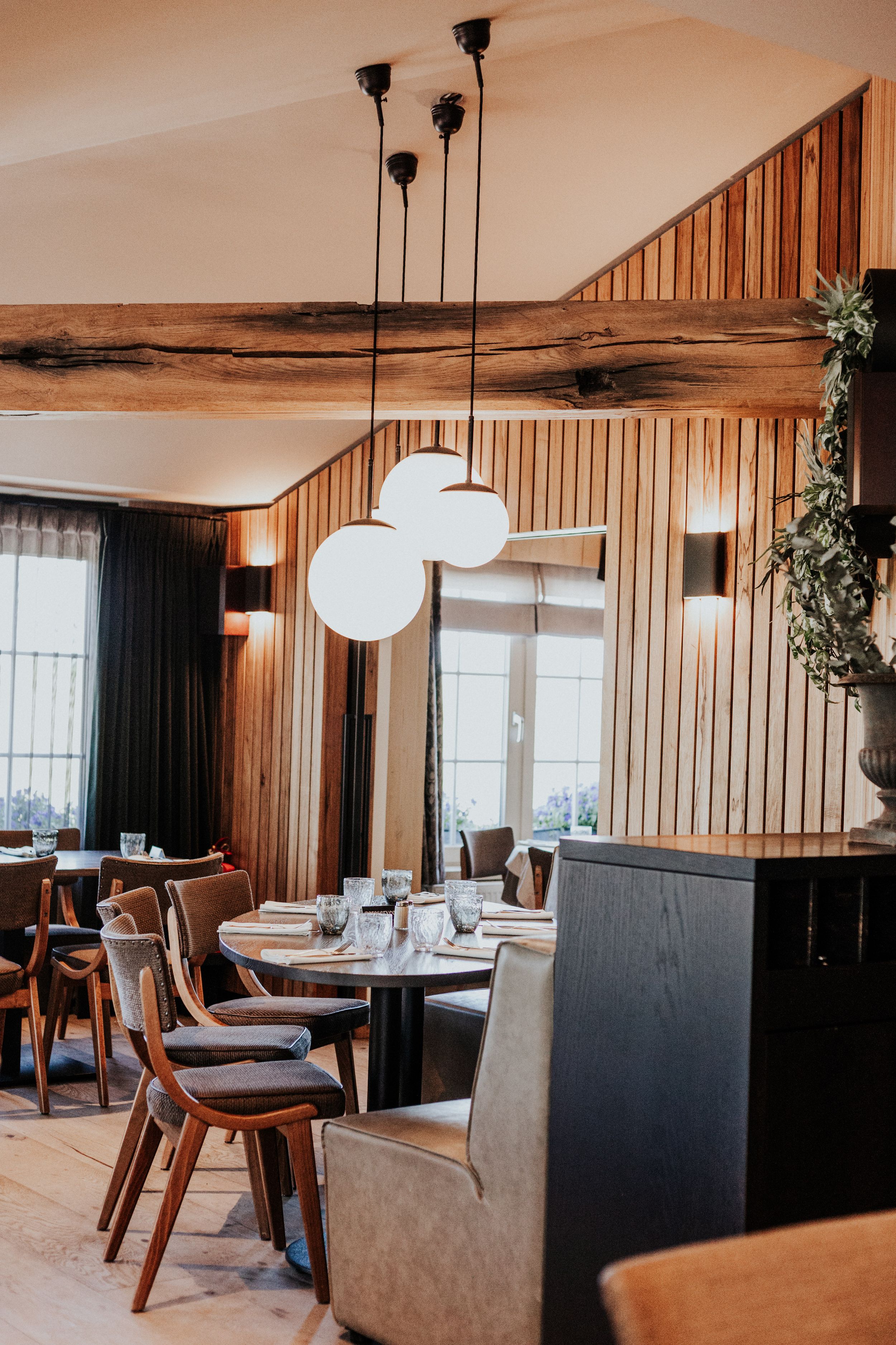 Modern restaurant interior with wood paneling, pendant lights, and comfortable seating arrangements.