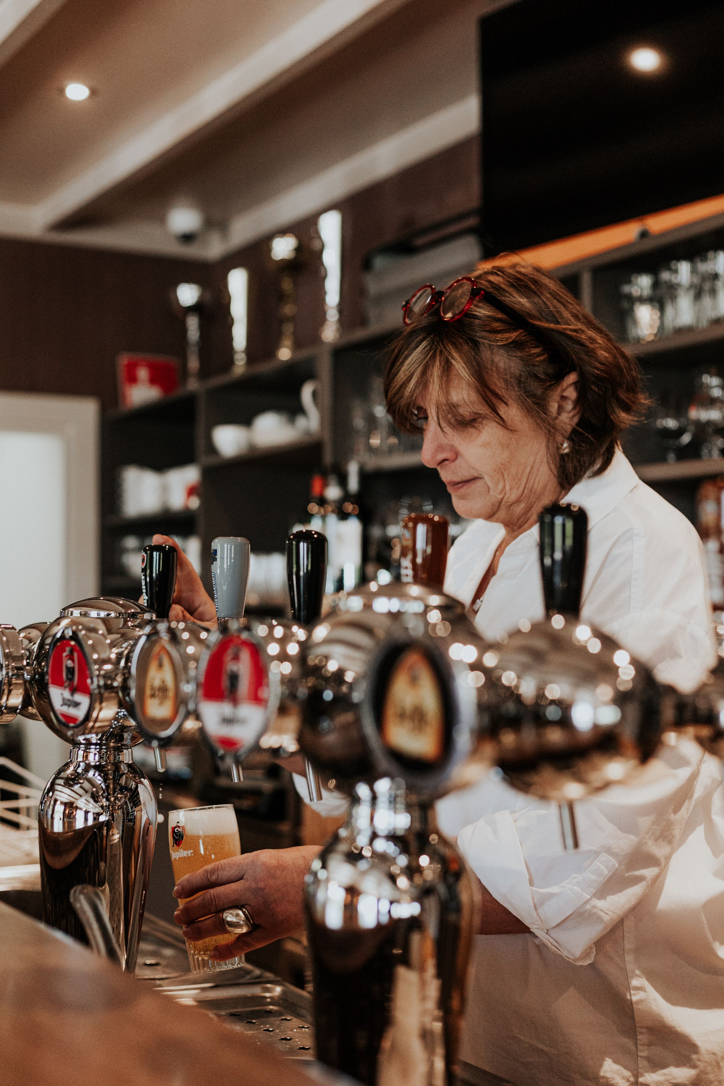Bar staff preparing drinks behind a well-stocked counter in warm lighting.
