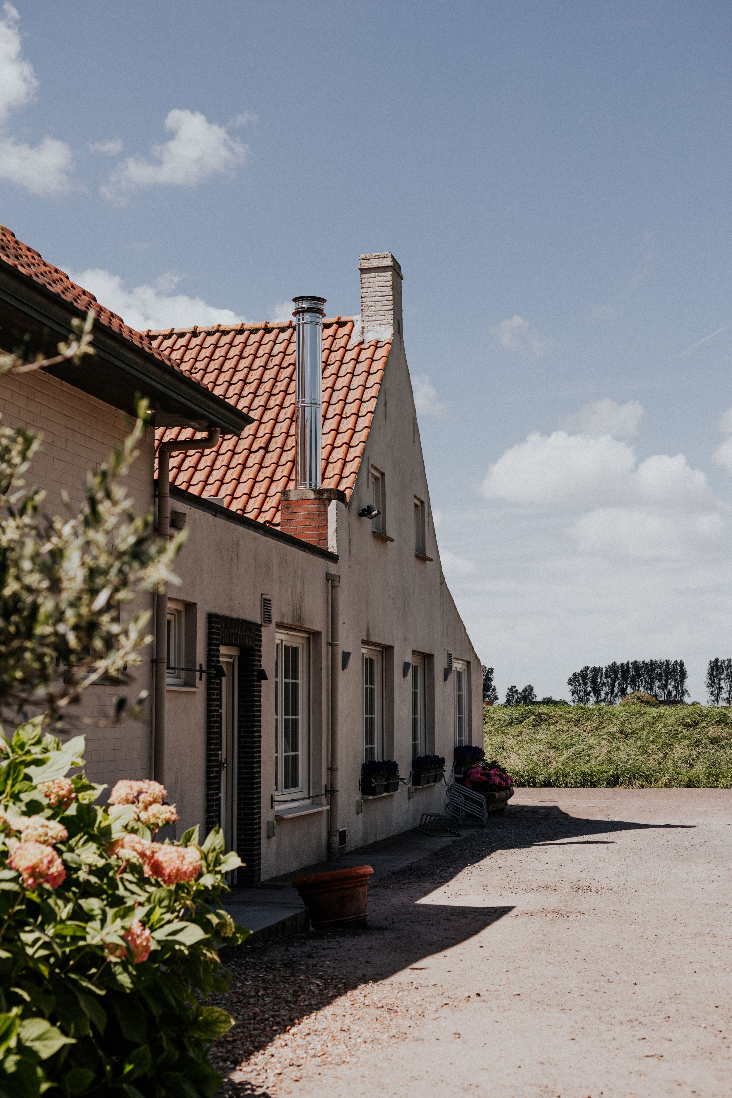 White farmhouse-style building with terracotta roof tiles and landscaped exterior.