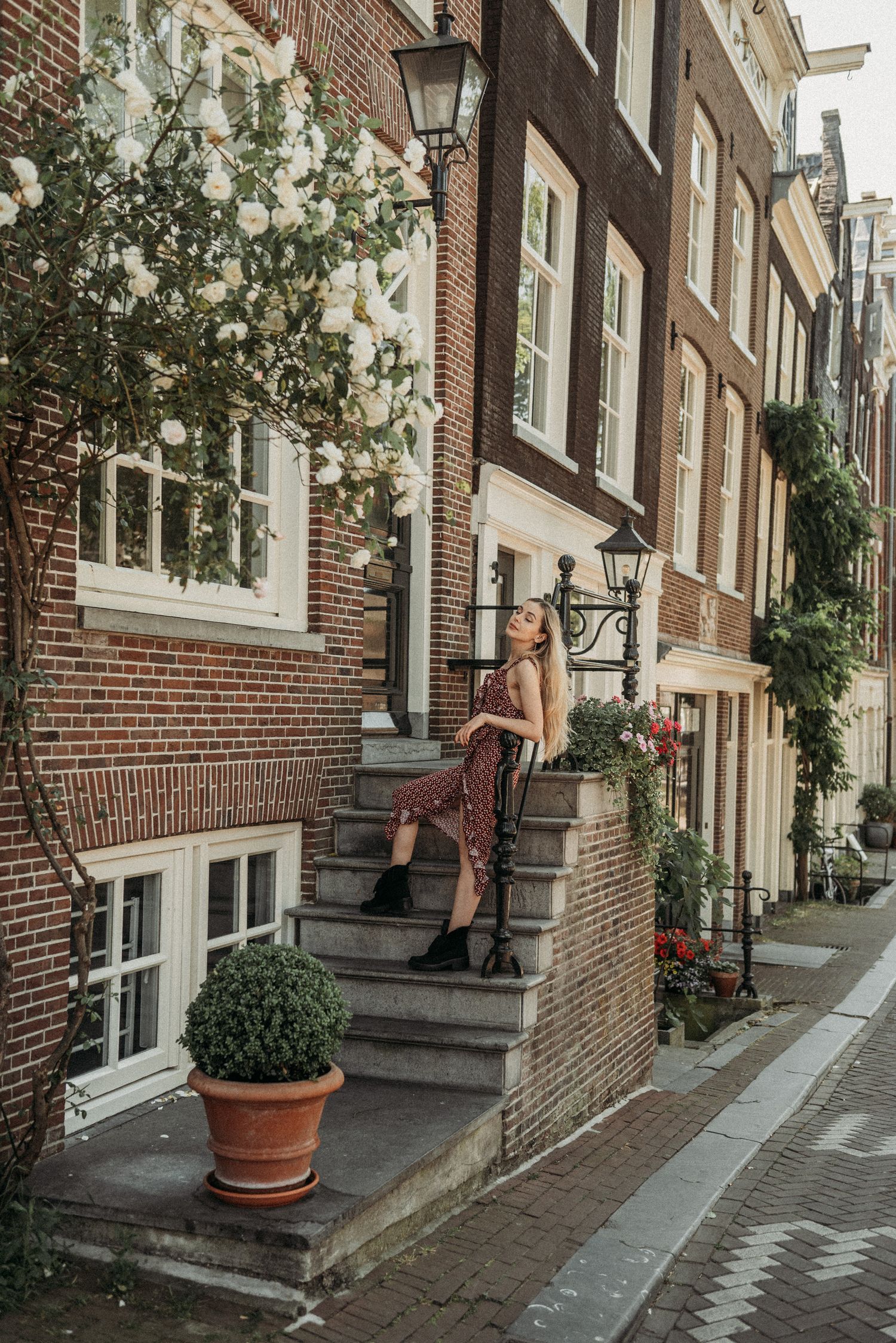 A woman in a summer dress sitting on the steps of a doorway in Amsterdam’s Jordaan district.