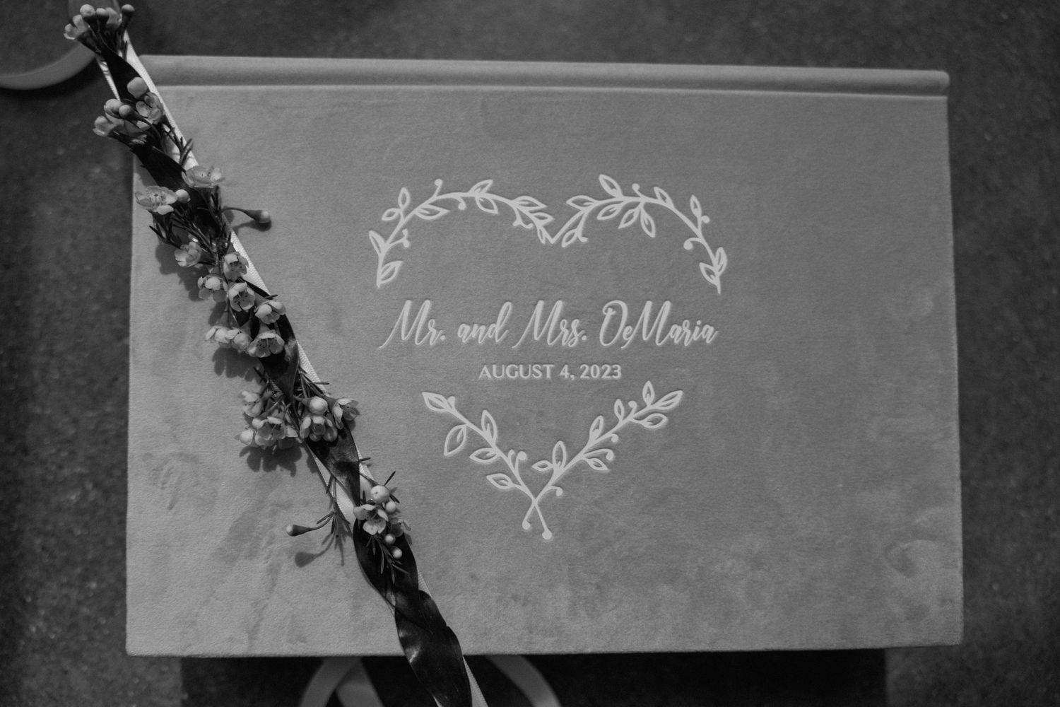 A black and white wedding sign with floral design displays 'Mr and Mrs DiNino' in elegant script.