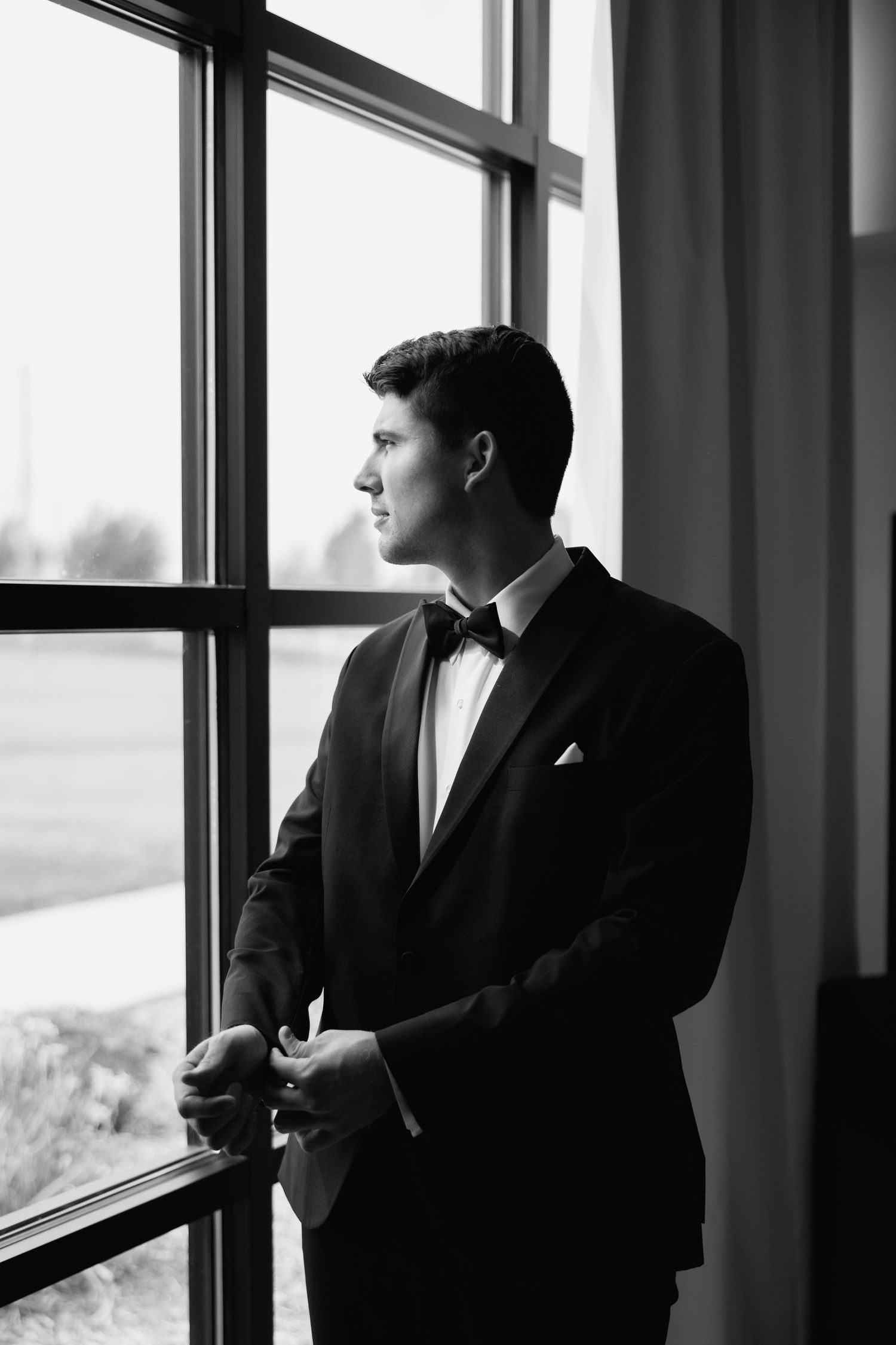 Black and white photo of a formal silhouette gazing through large windows.