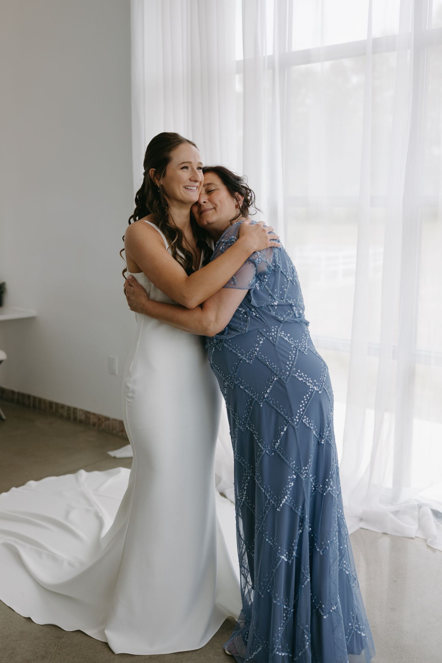 Emotional embrace between two people wearing white and blue formal dresses.