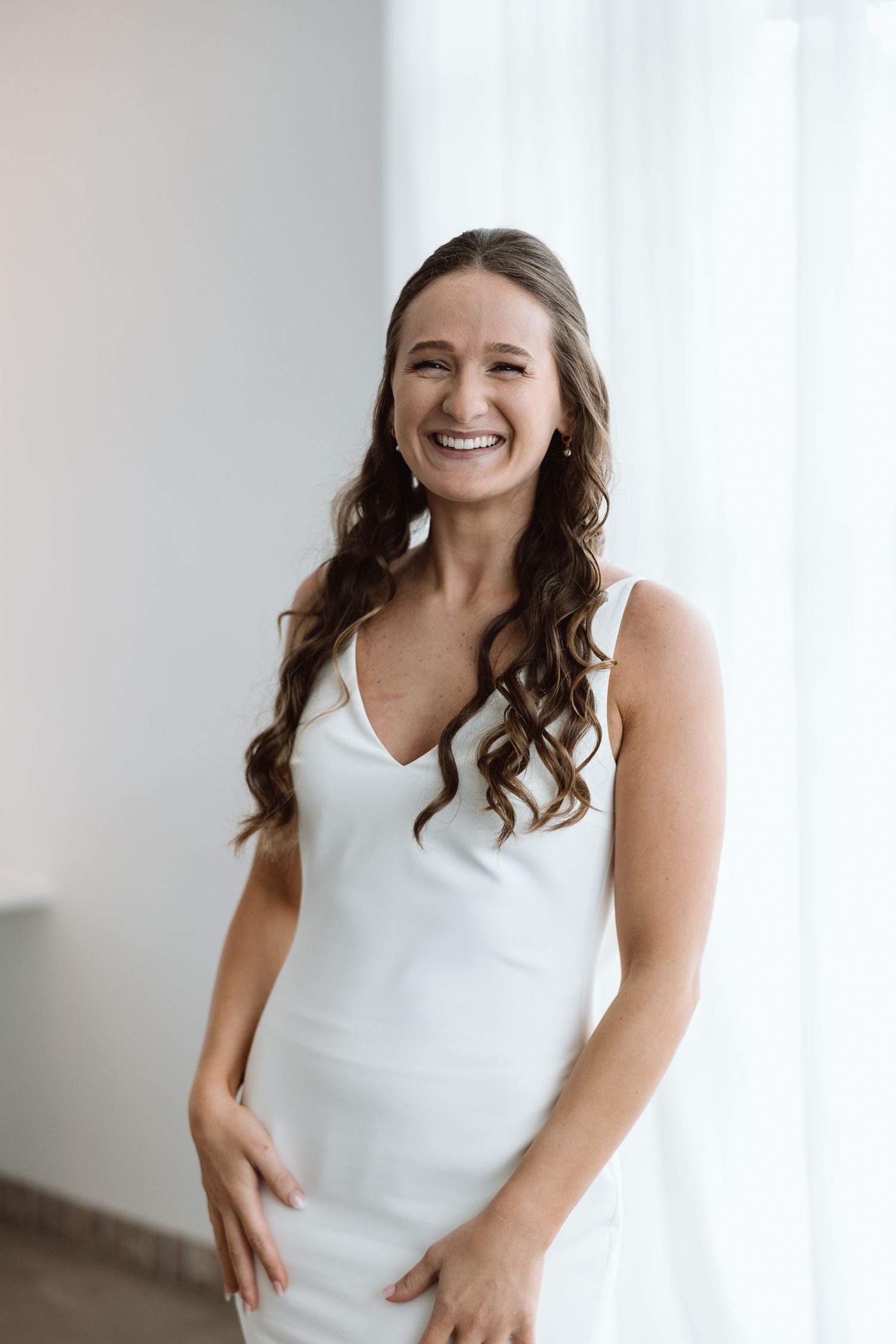 Natural light portrait against white curtains in an elegant setting.