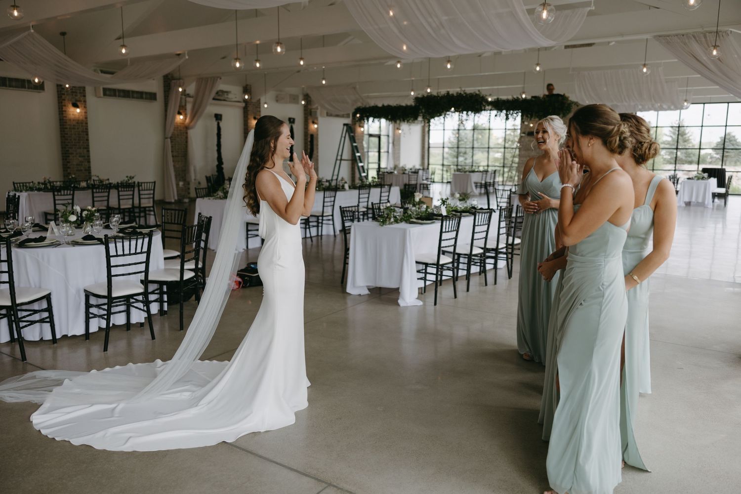 Wedding party first look reaction in an elegant reception venue with mint bridesmaid dresses.