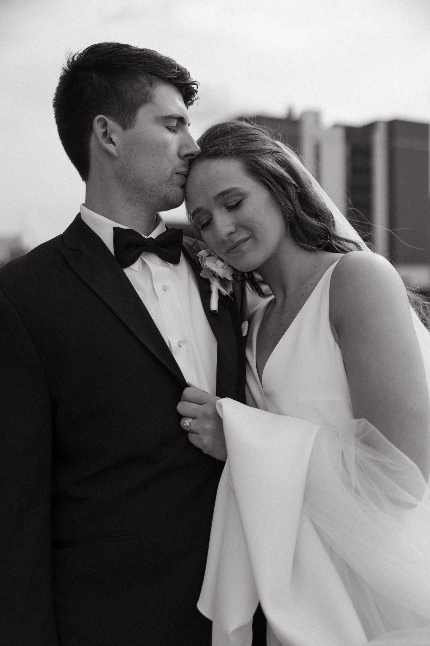 Intimate black and white portrait of couple in formal wedding attire.
