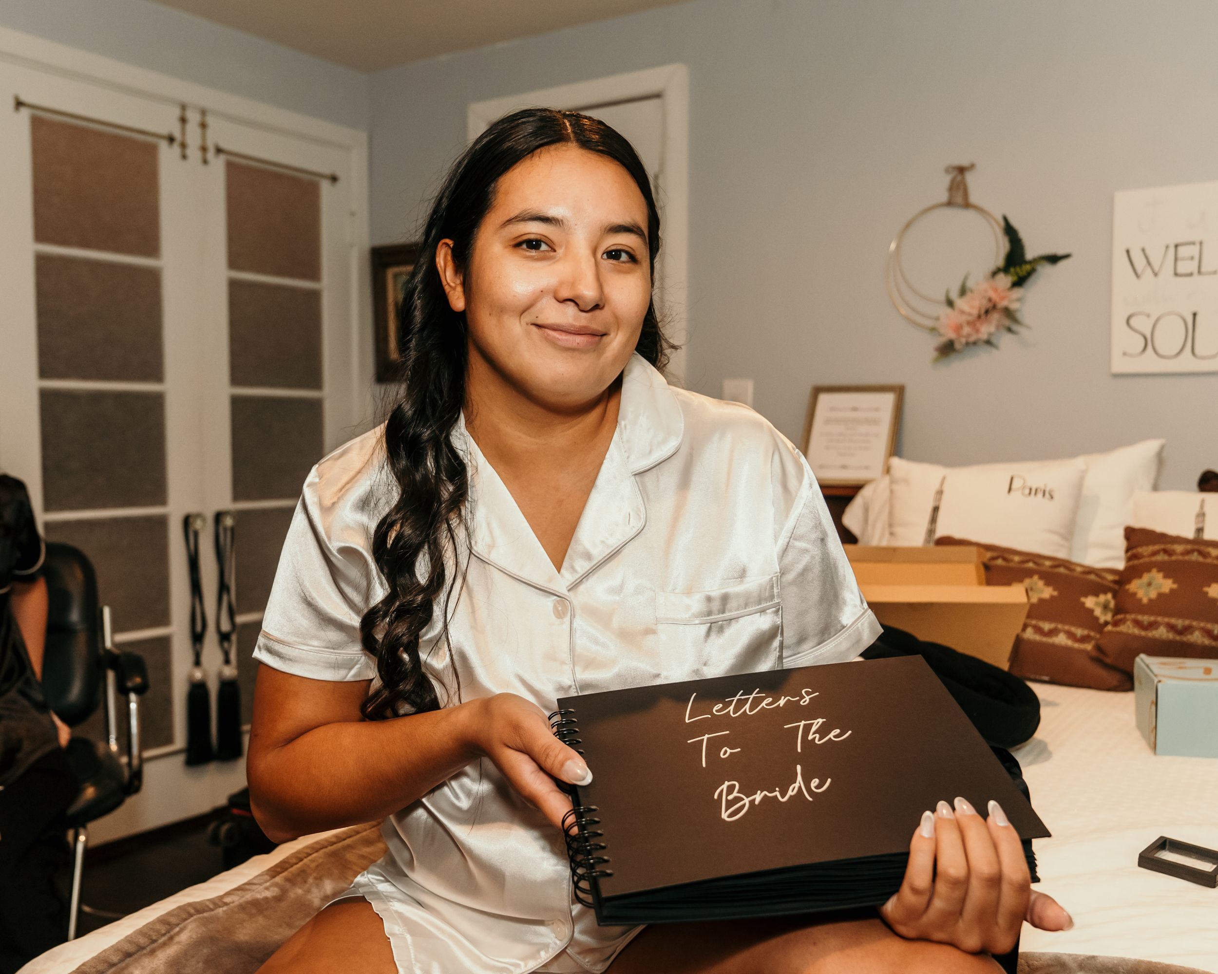 Wedding vendor in silk robe holding custom sign during preparation.