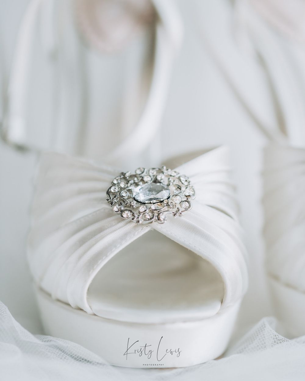 Professional product photography of White satin bridal shoes with a jewelled broach on the front by K Lewis Photography in Blackwood, Wales