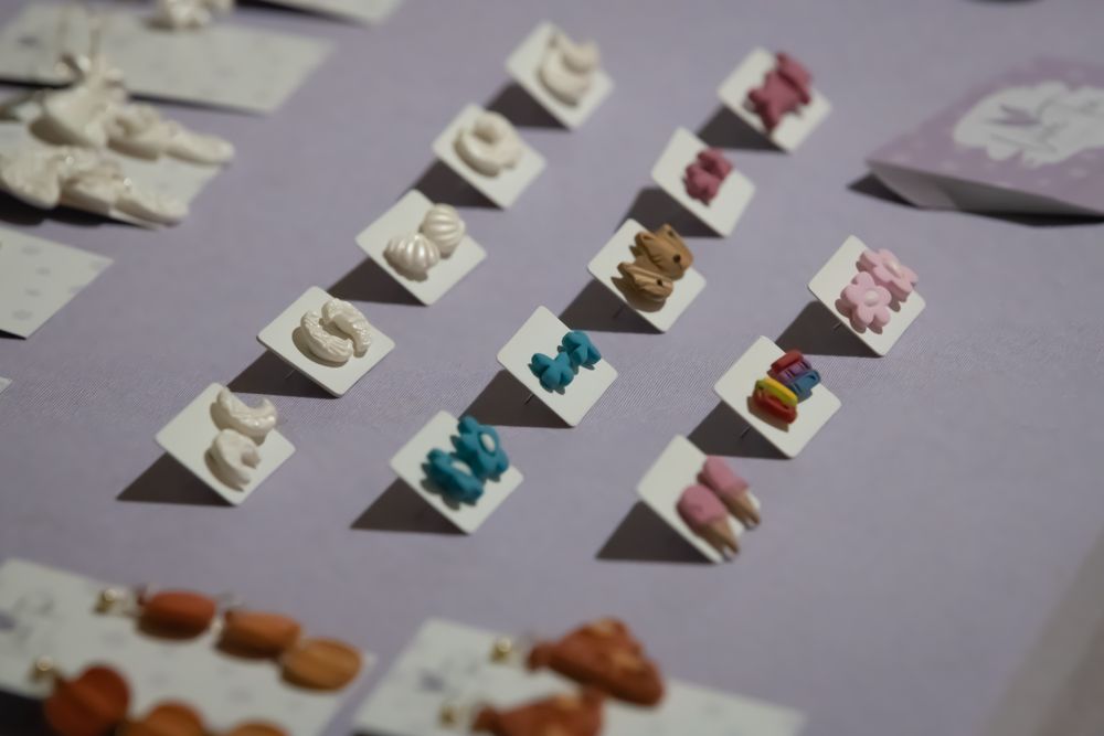 Handmade earrings displayed on card backs placed onto a lilac tablecloth. Product photography by K Lewis Photography