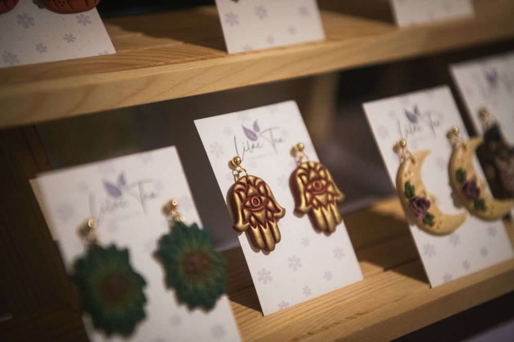 Handmade earrings displayed on a wooden tabletop display stand Product photography by K Lewis Photography
