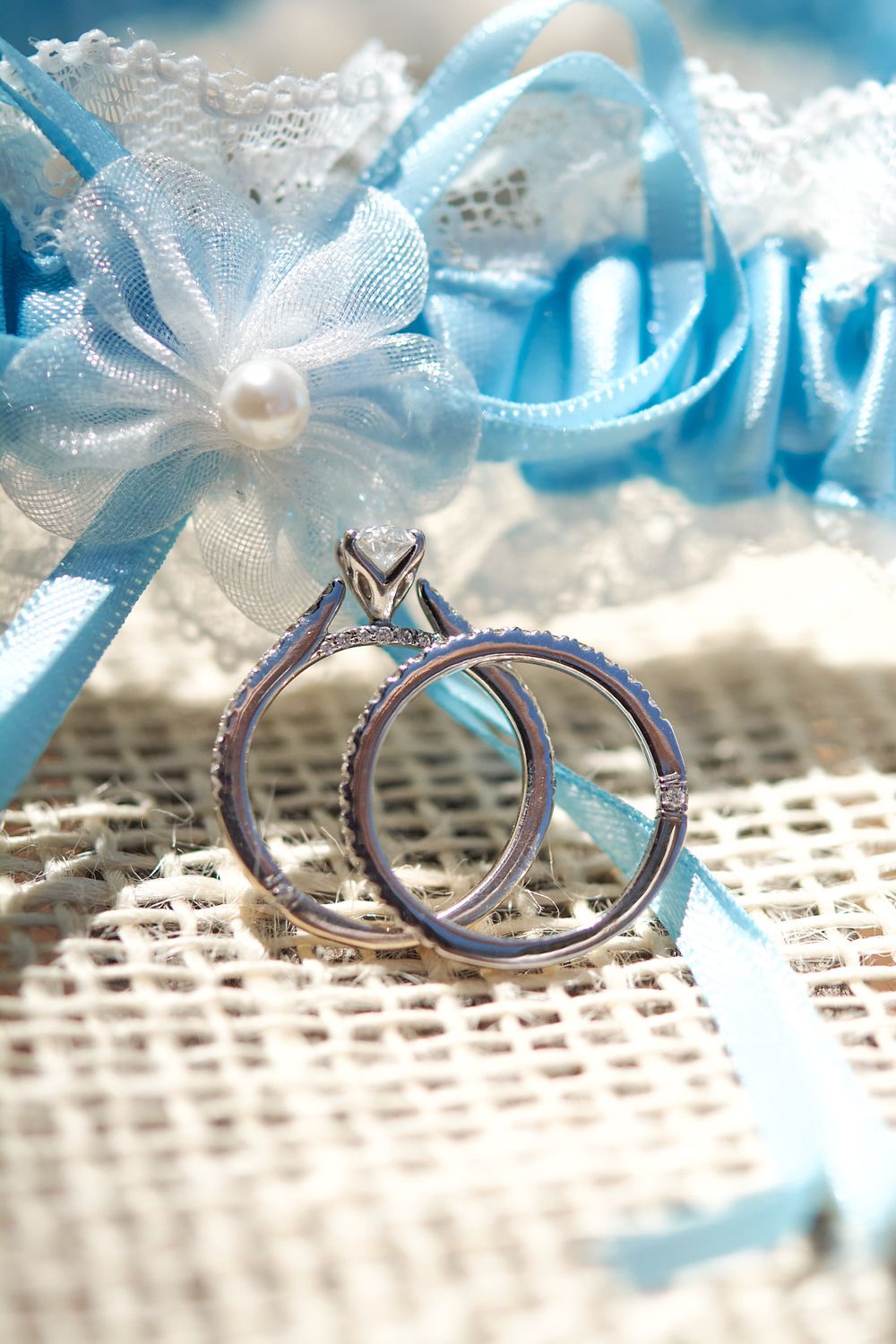 Close up image of the bride's wedding and engagement rings with her blue garter