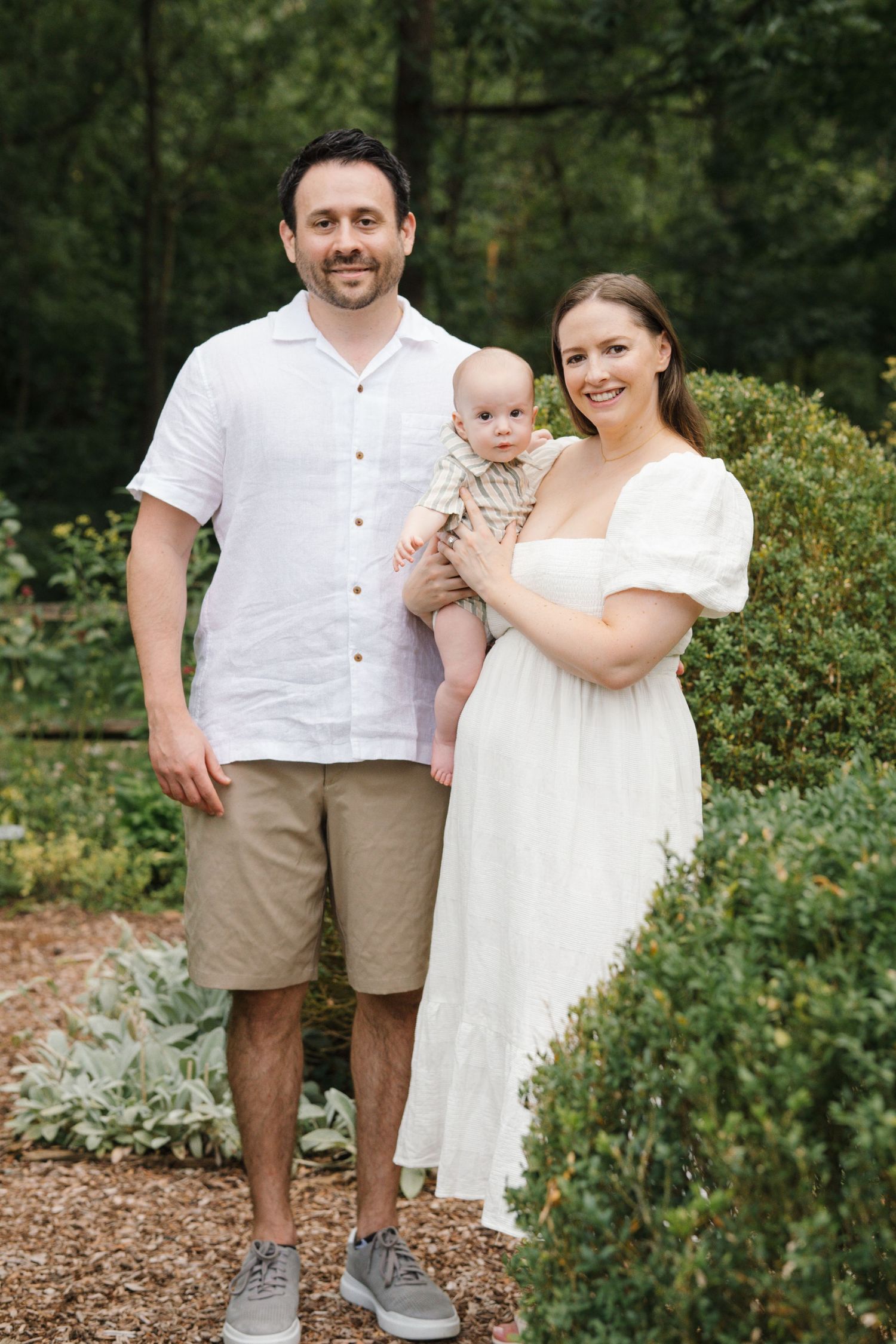 Family standing in a vibrant herb and wildflower garden at Barclay Farmstead, smiling at the camera under soft overcast skies in Cherry Hill