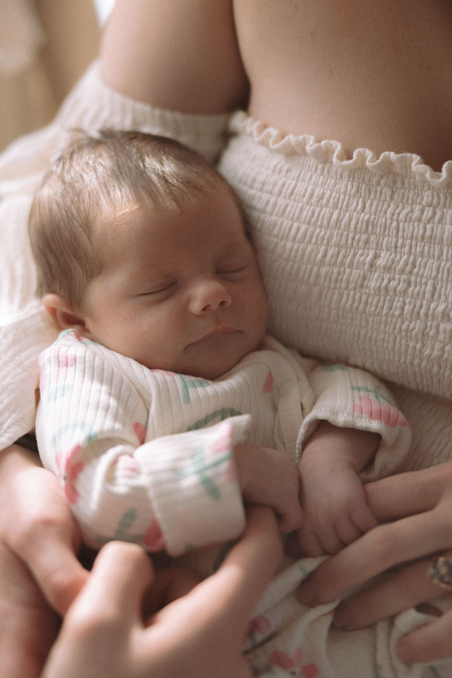A sleeping baby in white clothing lies peacefully on a textured white surface.