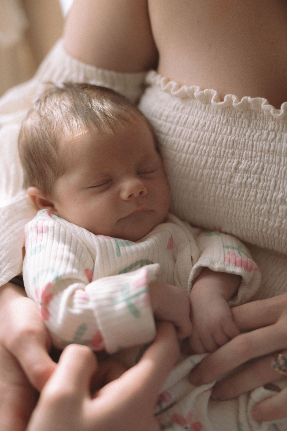 A sleeping baby in white clothing lies peacefully on a textured white surface.