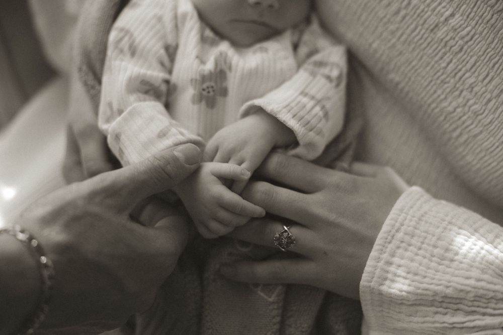 A series of black and white photos showing hands gently holding and examining a small baby.