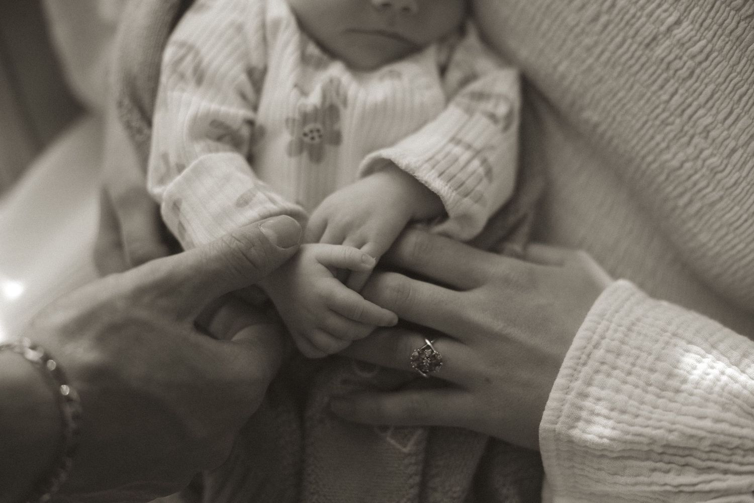 A series of black and white photos showing hands gently holding and examining a small baby.