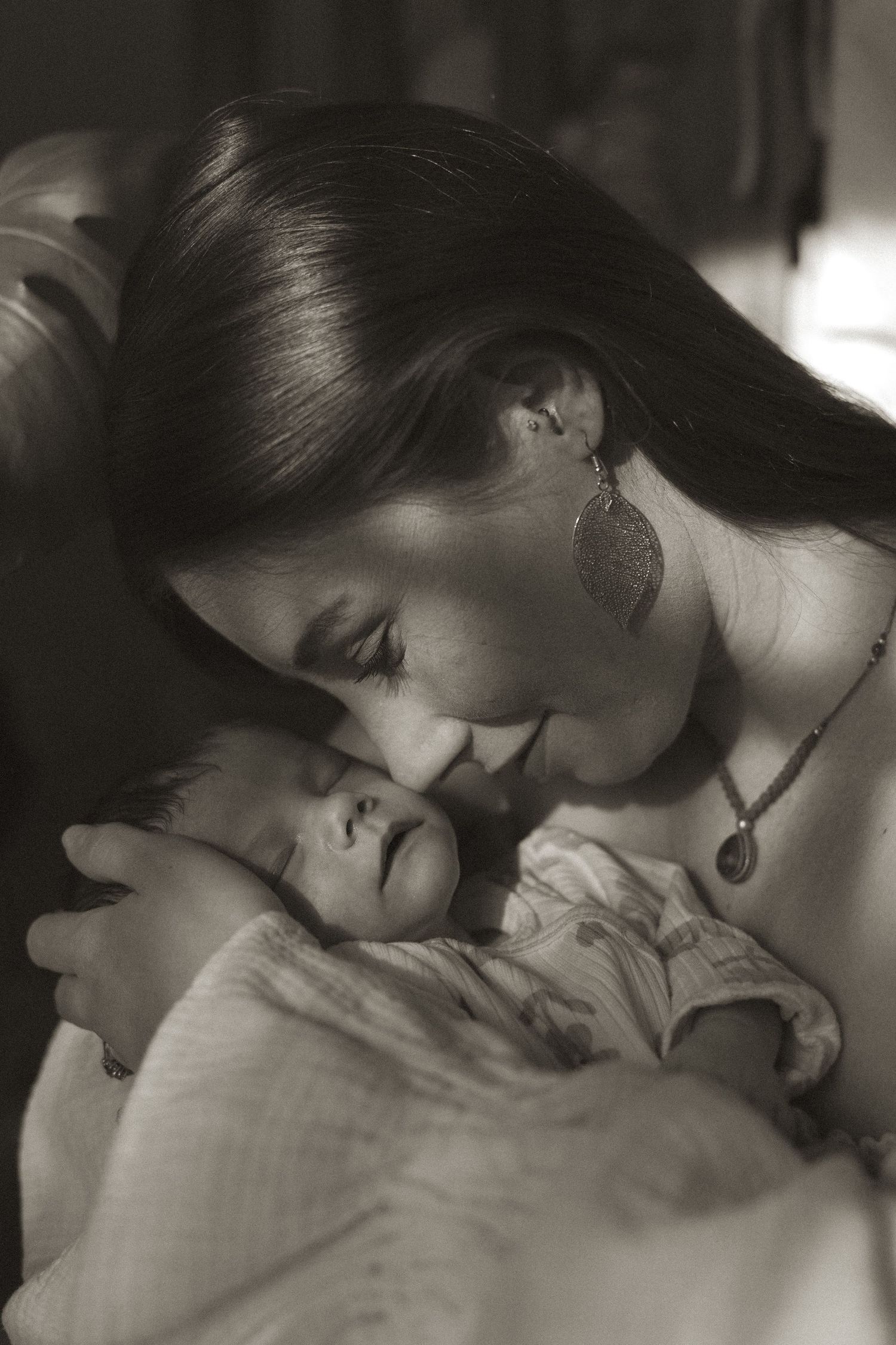 A tender black and white photo sequence showing a mother gently kissing and bonding with her newborn baby.