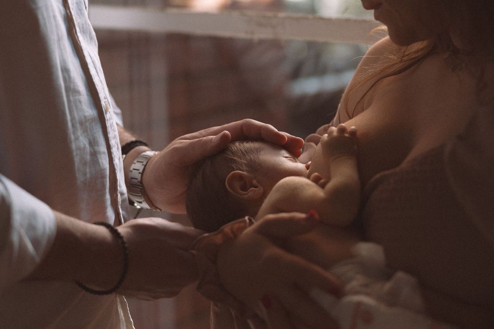 A newborn baby receives tender care during a precious bonding moment in warm, gentle lighting.