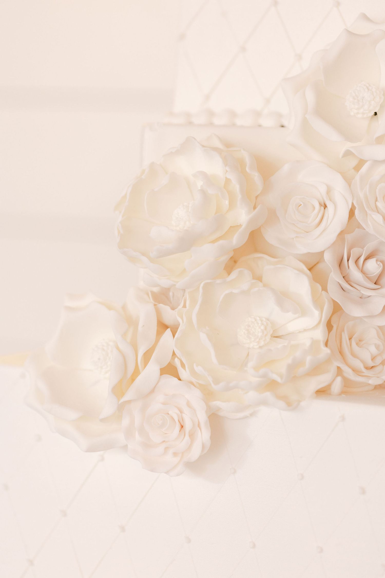 Soft white silk roses arranged artistically on pale background.