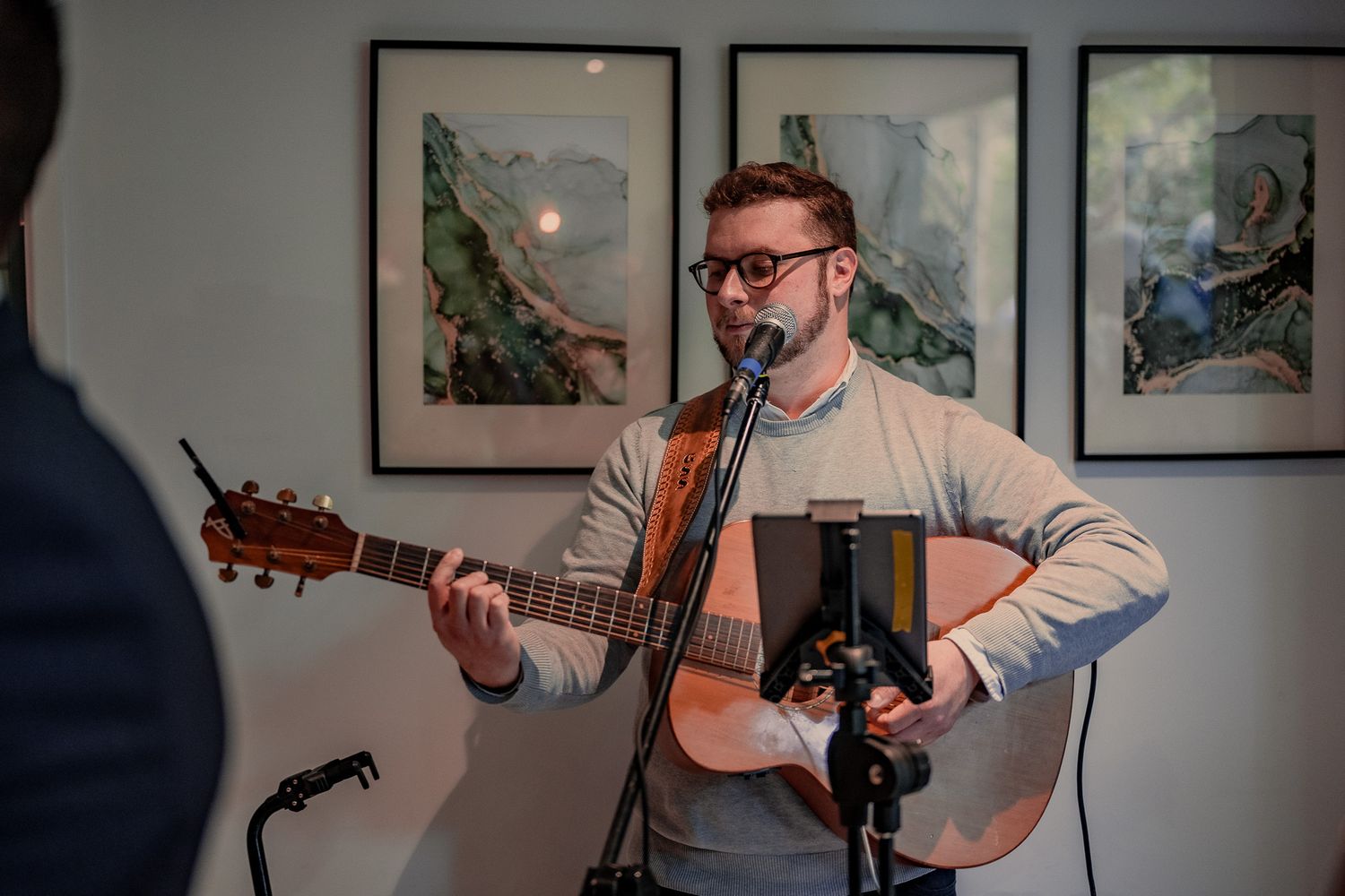 A musician performs on acoustic guitar during an intimate indoor wedding reception.