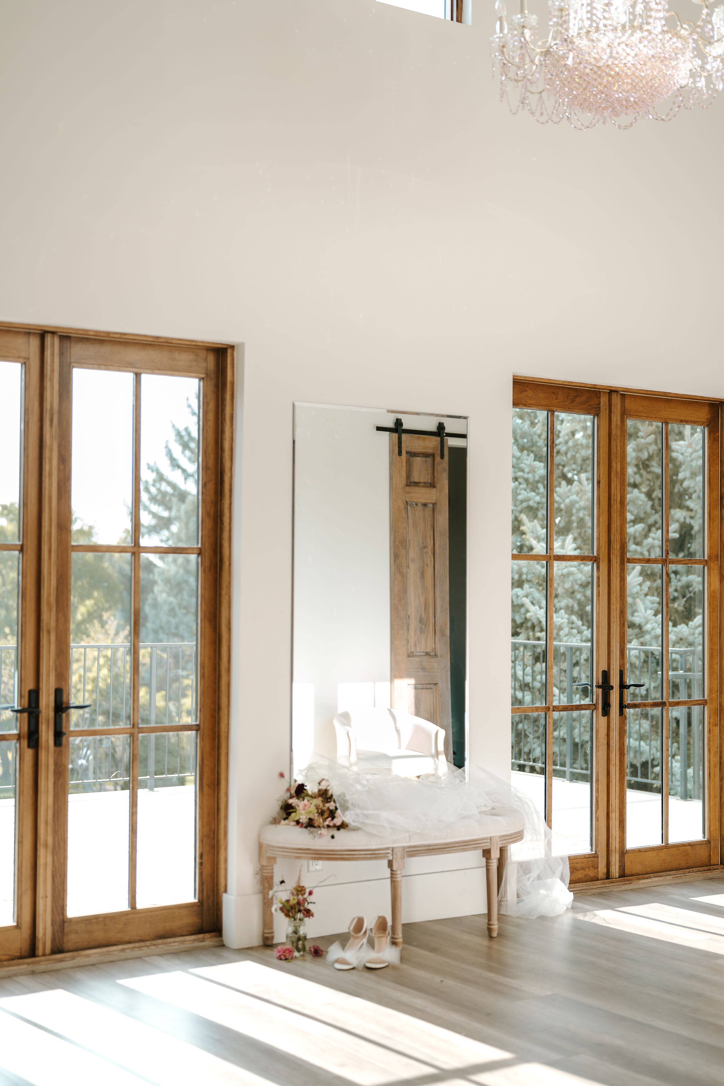 Bright modern bridal suite with French doors, chandelier and white vanity table.
