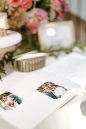 Wedding guest book table with floral decorations and photo display.