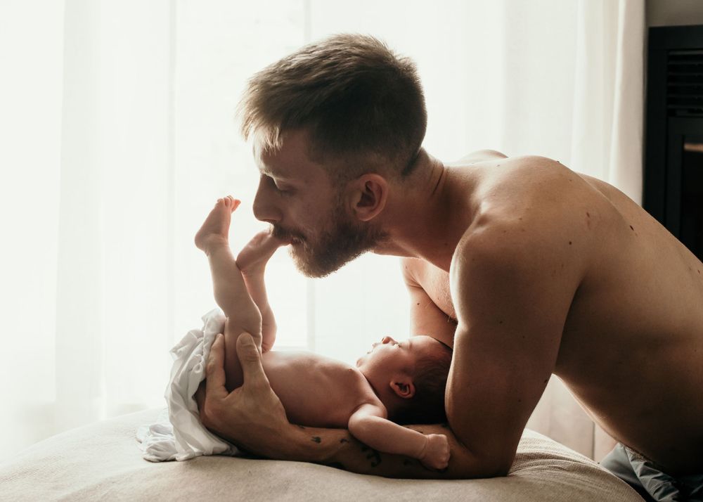 Tender moment captured between parent and newborn in soft window light.