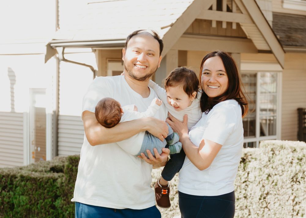 A happy family portrait outside their house on a sunny day.