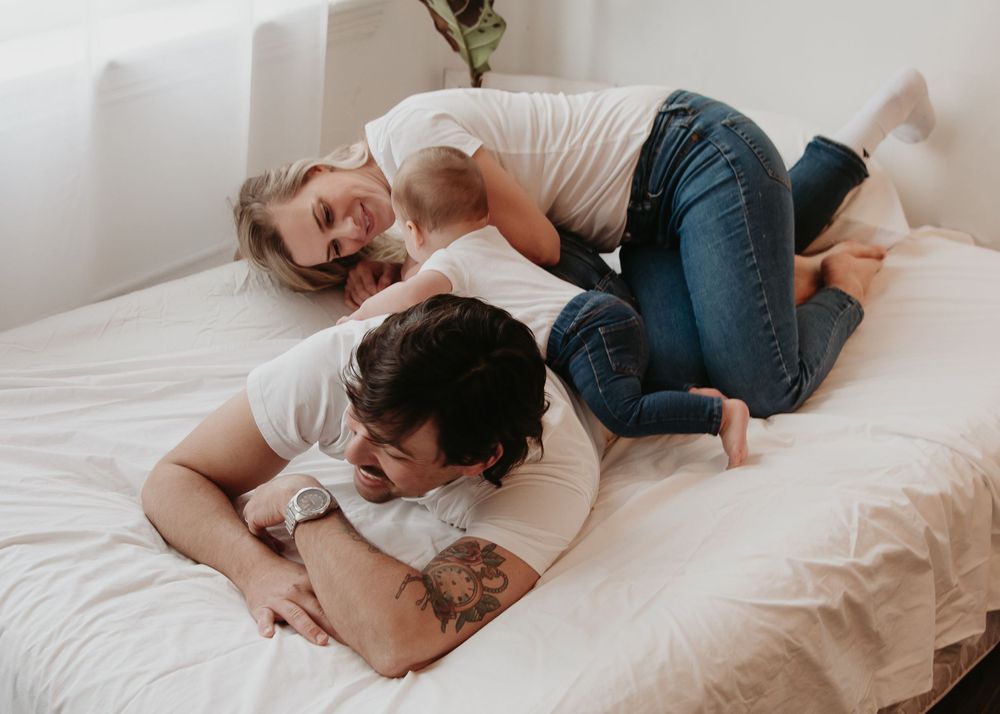 A playful moment between family members on a white bed.