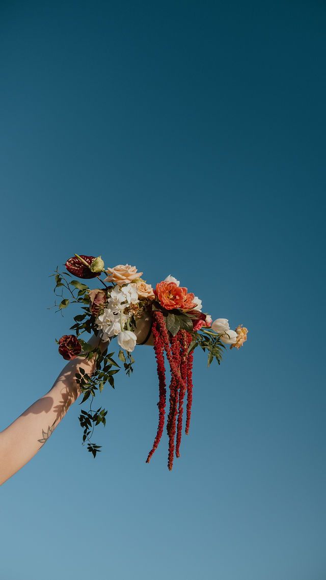 Colourful bouquet purse against clear blue sky. Howdy Pictures, fun laidback wedding photographers on film & digital in New Zealand
