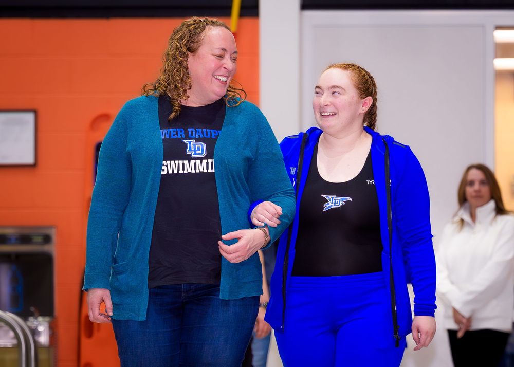 Lower Dauphin senior swimmer stands with a family member on the pool deck during Senior Night celebration.