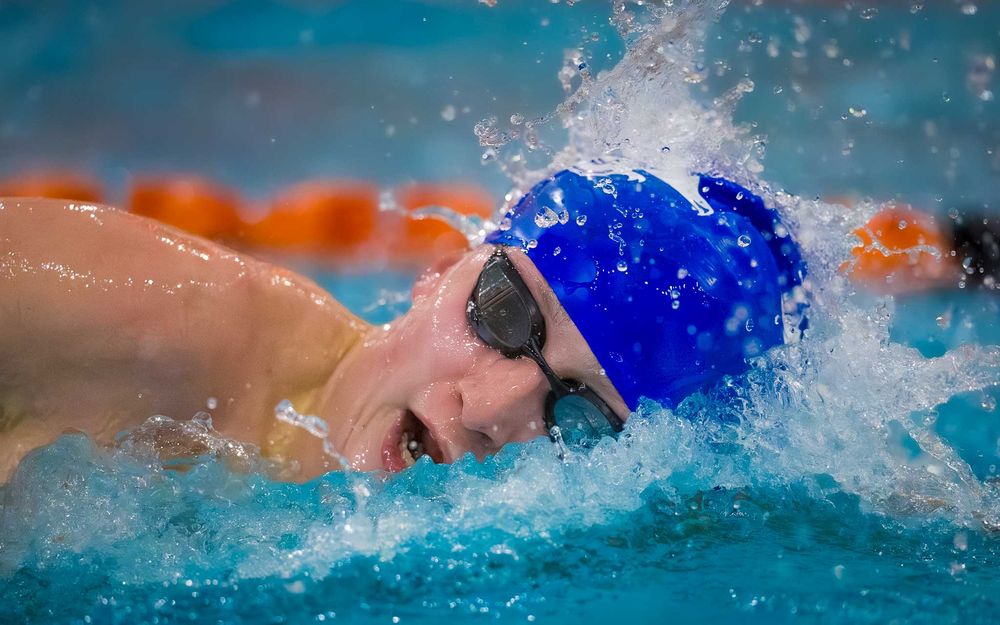 Lower Dauphin swimmer in blue cap swimming breaststroke during Senior Night festivities.