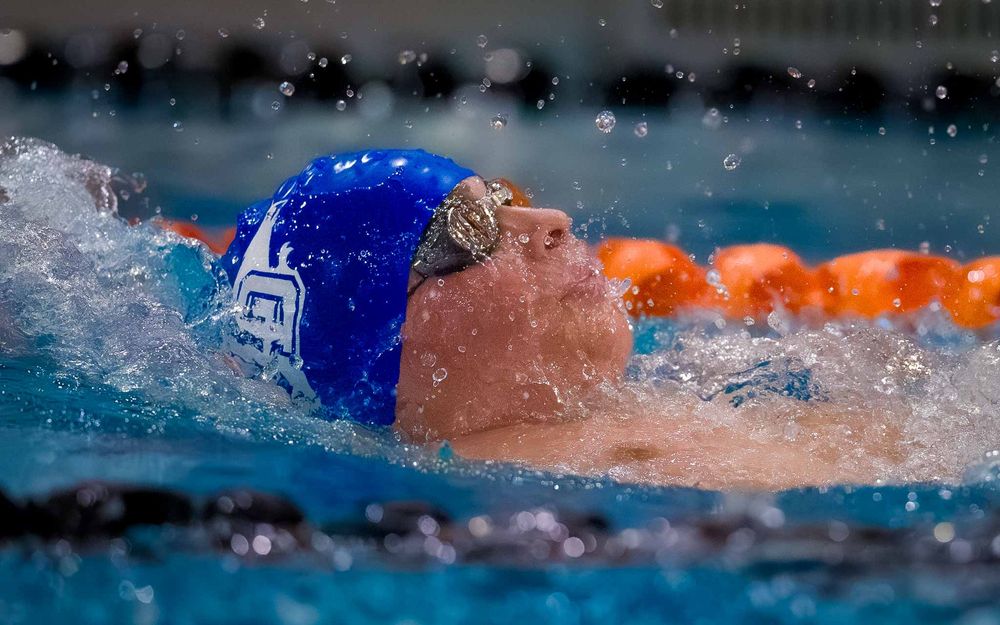 Lower Dauphin swimmer in blue cap swimming backstroke in the pool during Senior Night.