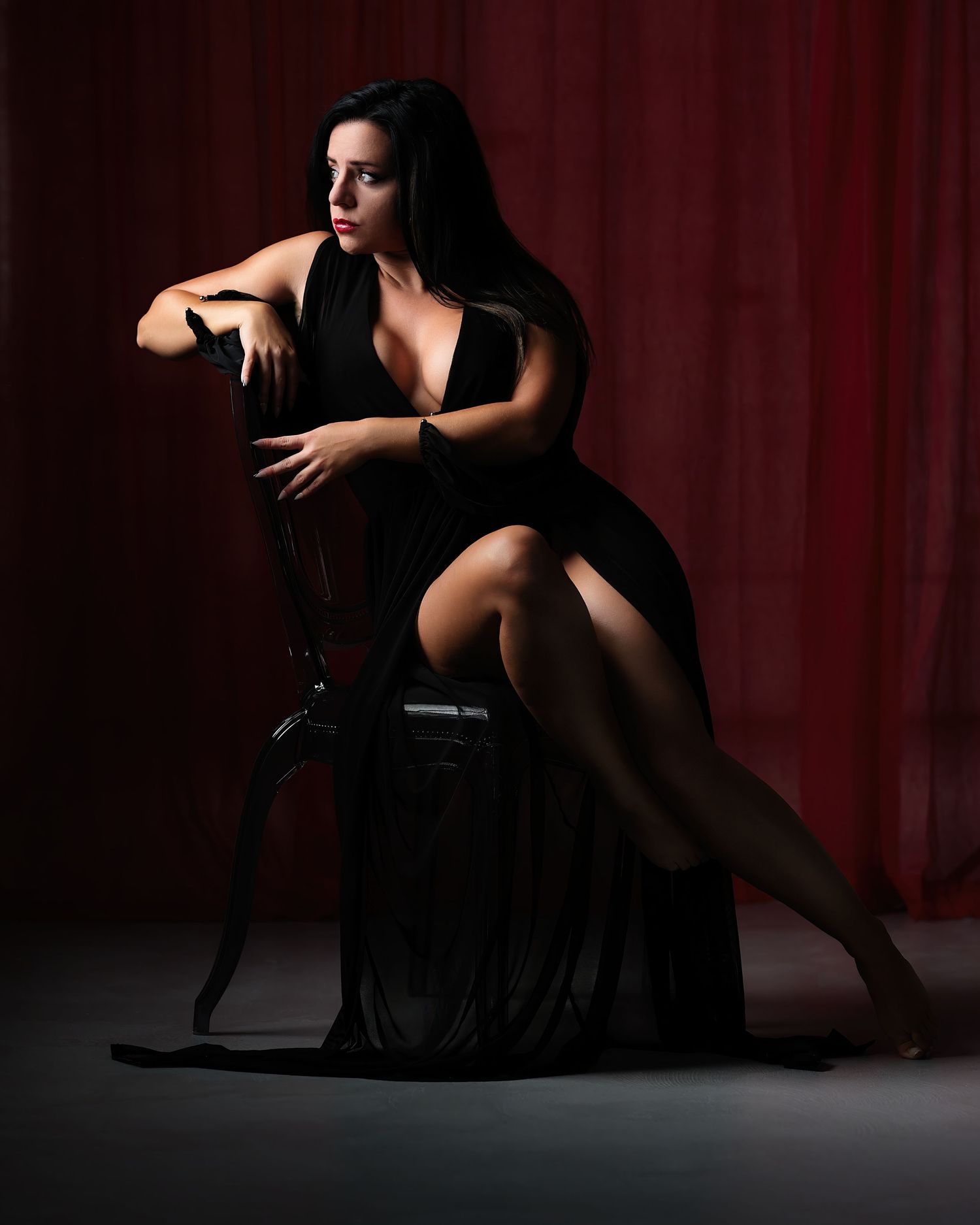 David G Holt Photography - Artistic boudoir photoshoot with red curtain backdrop and dramatic lighting in dark setting.