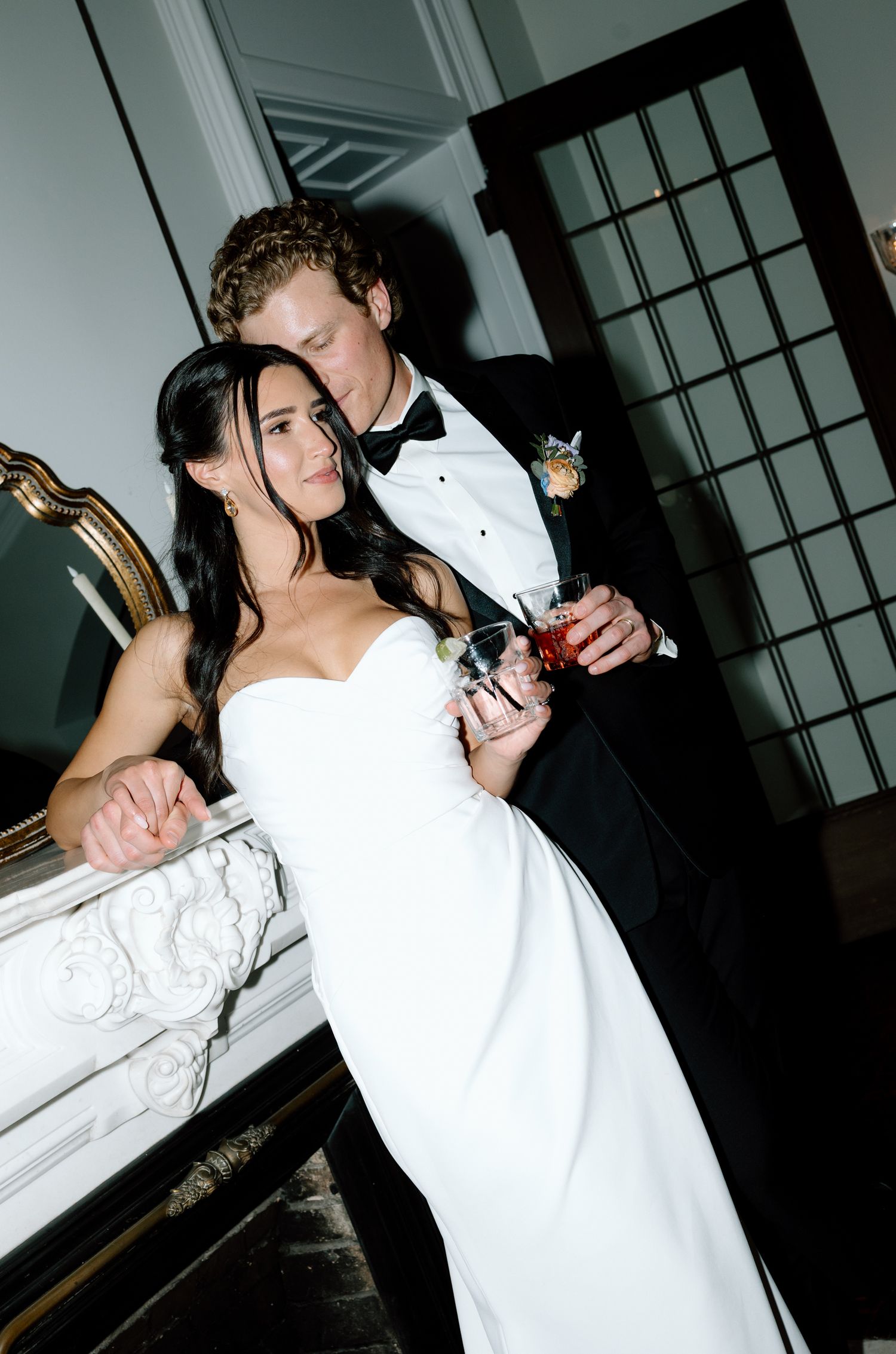 A couple in formal wedding attire share an intimate moment at their reception, with the bride in a white gown.