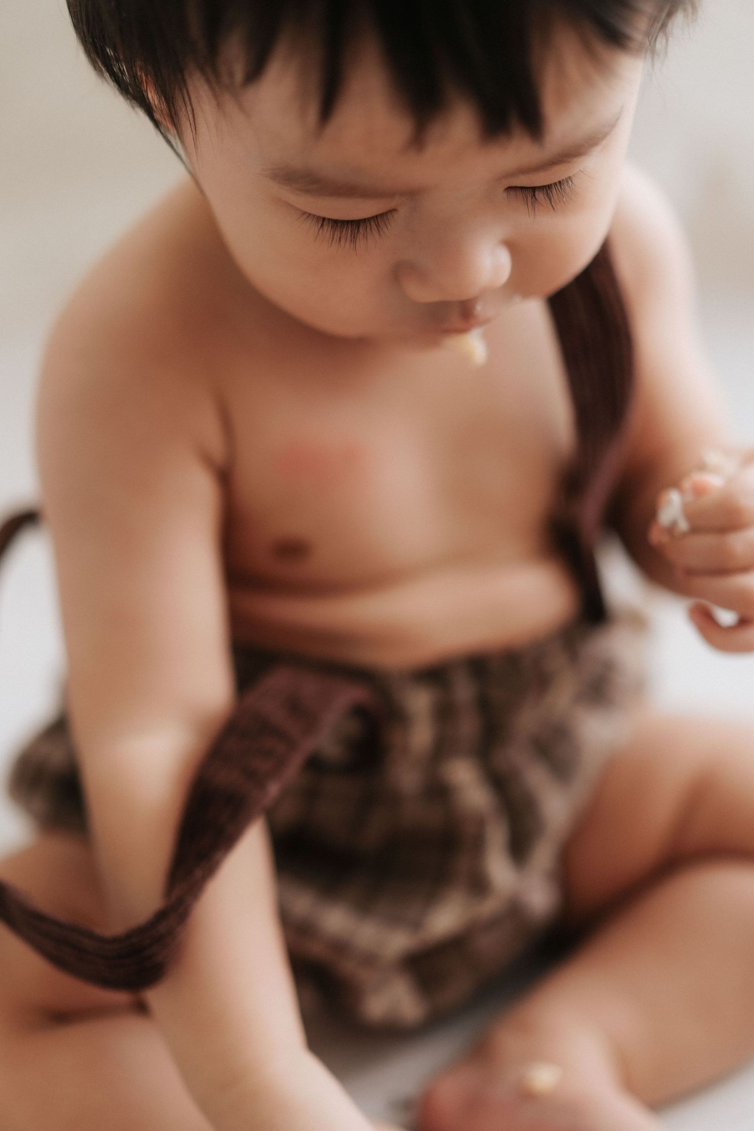 Close-up series showing a baby in brown clothing exploring and playing from different angles in soft lighting.