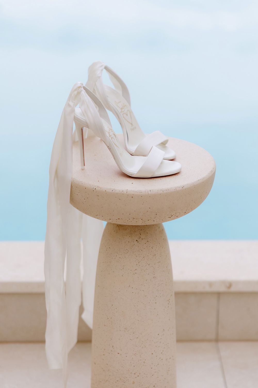 A minimalist sculpture of a white tissue box holder with a cylindrical base and curved top platform in beige tones.